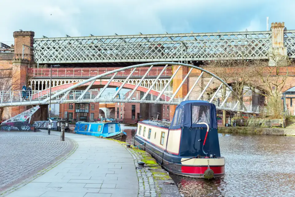 Narrowboats moored on a canal beneath iron bridges