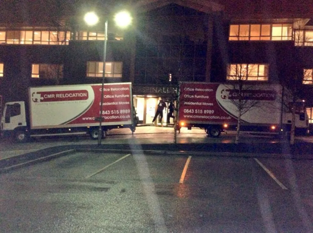 Two CMR Relocation lorries loading outside an office at night
