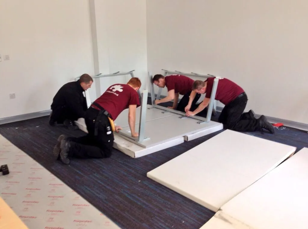 CMR Relocation crew in branded shirts assembling an office desk