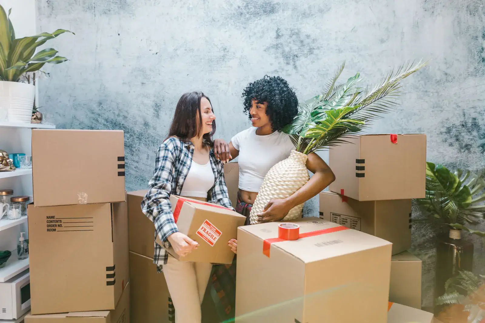 Two friends laughing among packed boxes on moving day