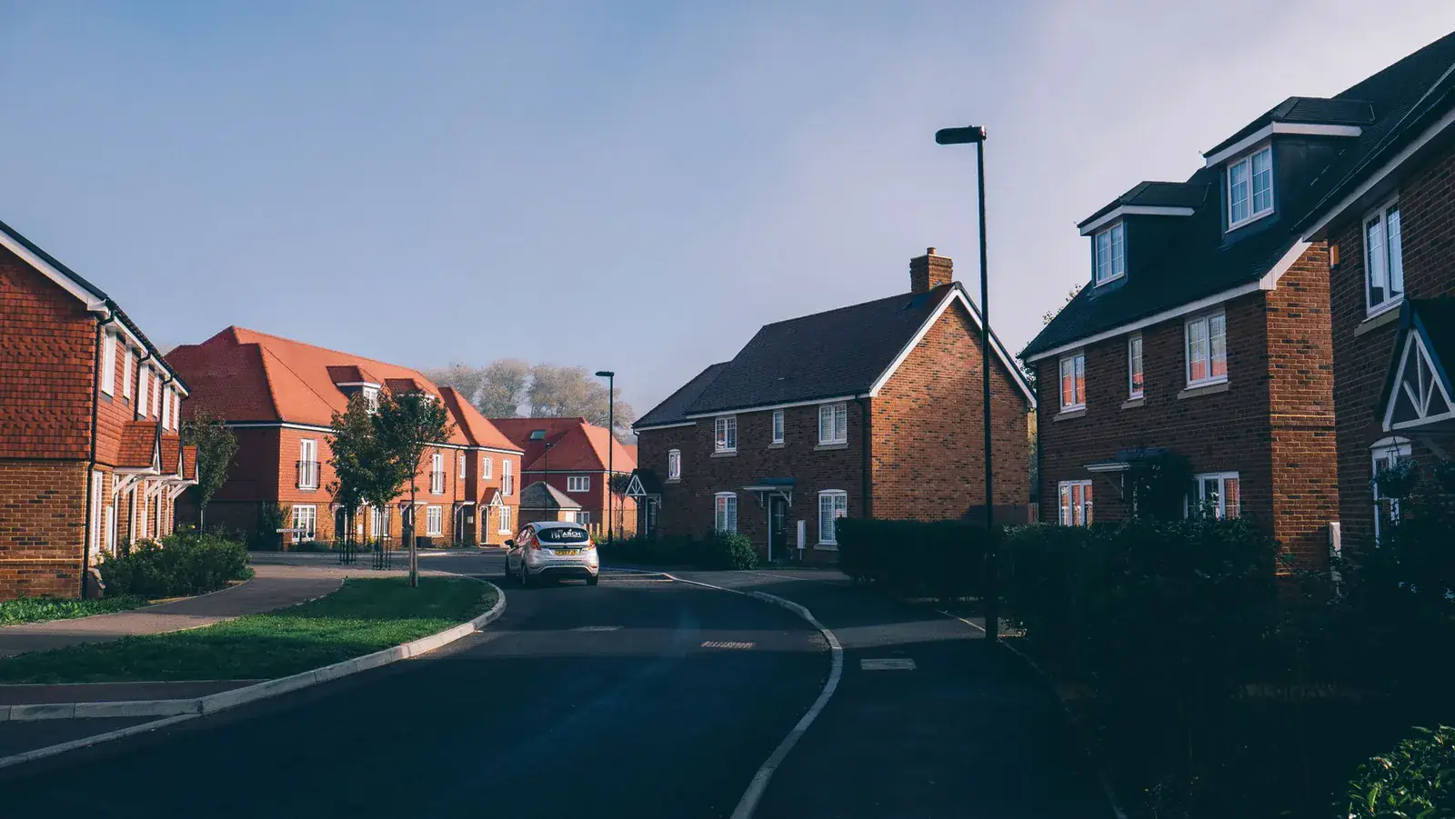 Curving road through a modern estate of red-brick new-build houses