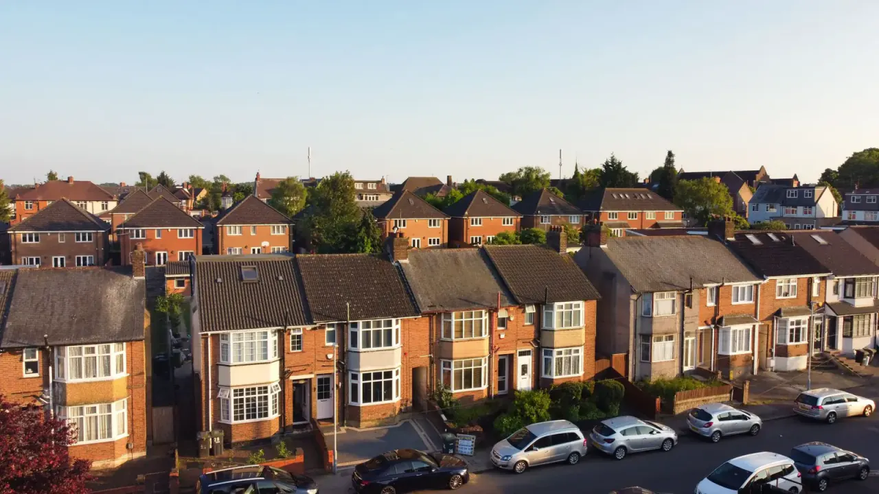 Row of brick semi-detached houses with cars parked on the driveways