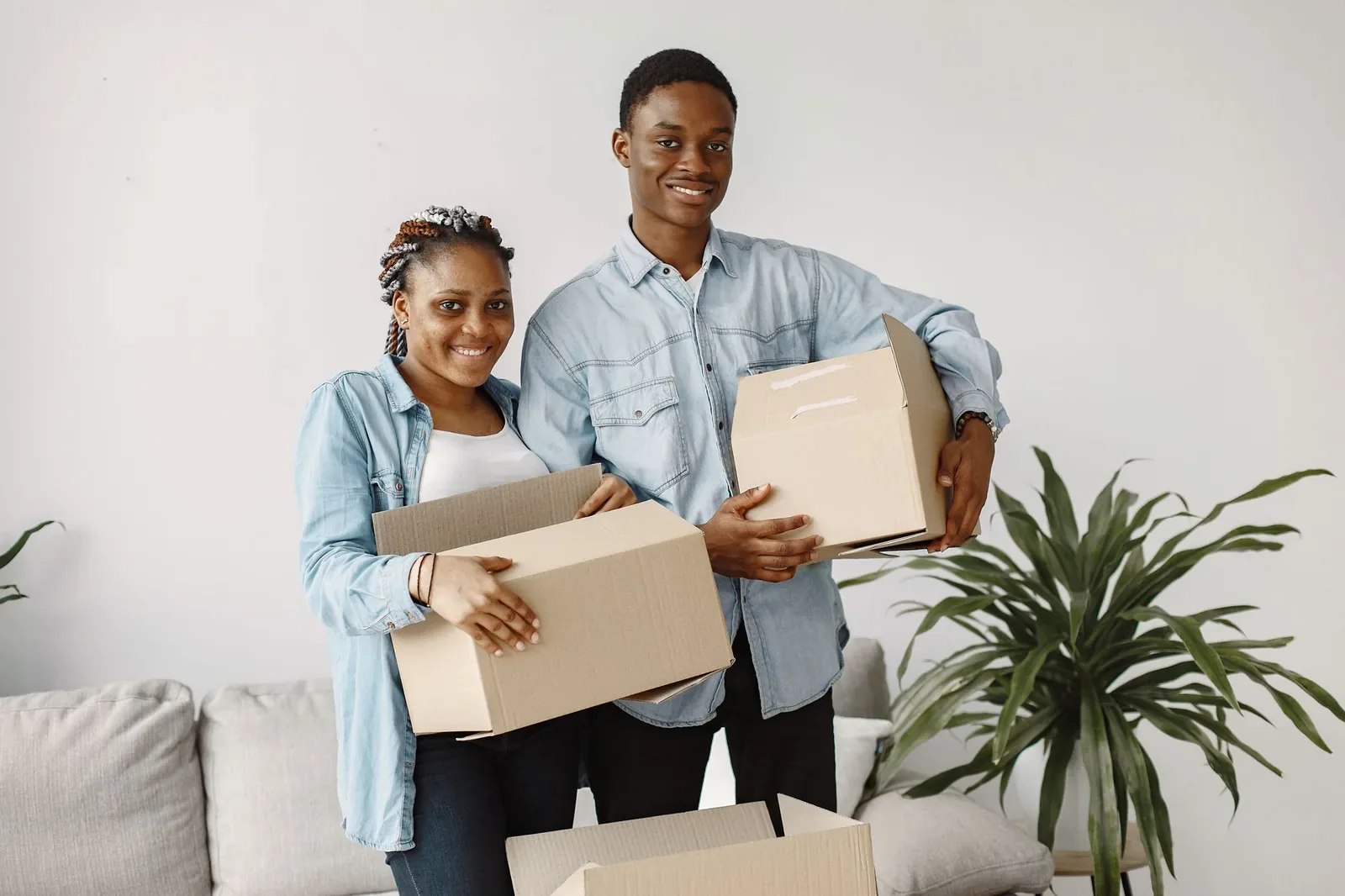 Smiling couple holding cardboard boxes in their new living room