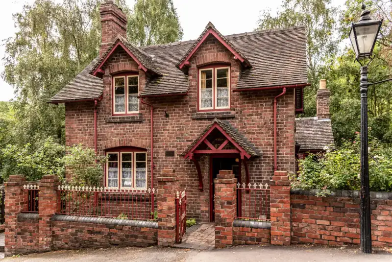 Victorian red-brick house with gables behind a garden wall