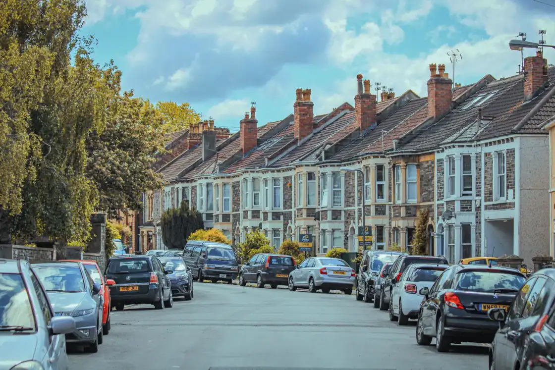 Street of Victorian bay-fronted terraced houses with cars parked on both sides