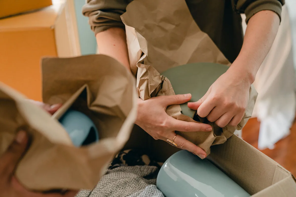 Hands wrapping fine china in packing paper before a house removal in Hale